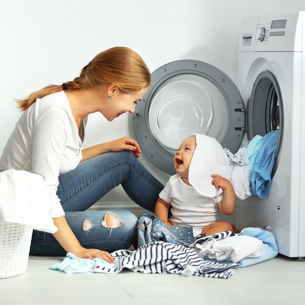 mom and baby in front of efficient laundry machine