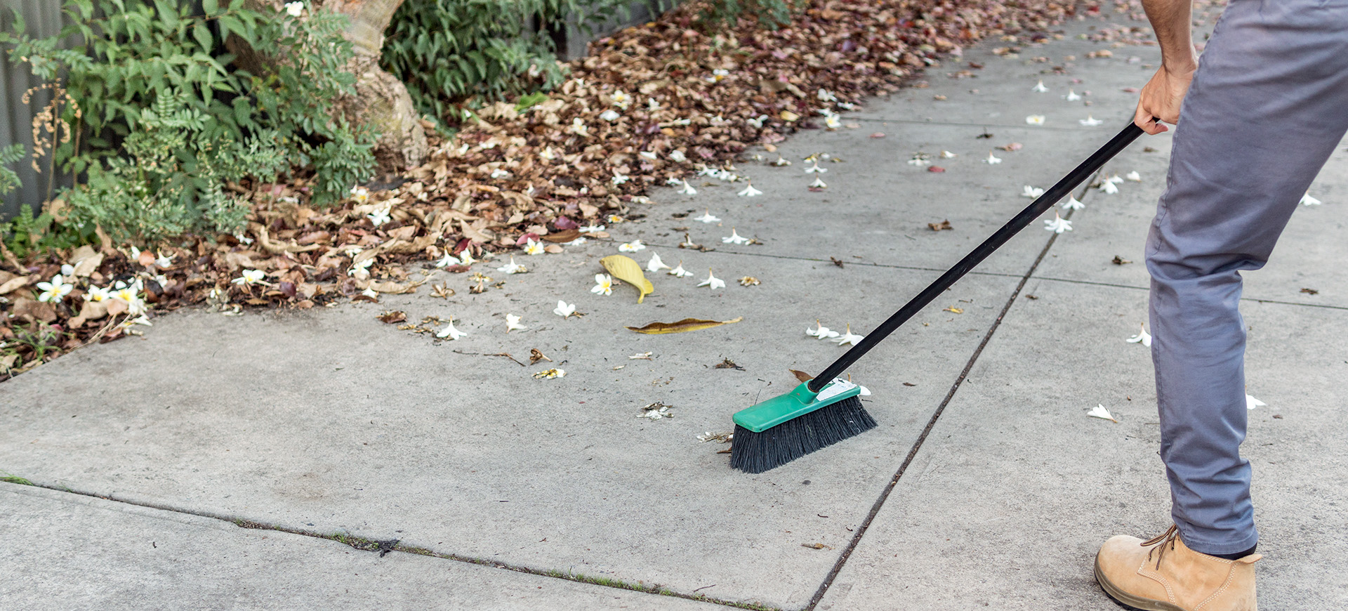 Man sweeping the driveway with a broom