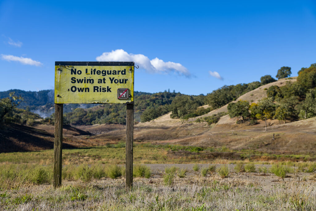Dry lakebed with sign, "No Lifeguard Swim at Your Own Risk