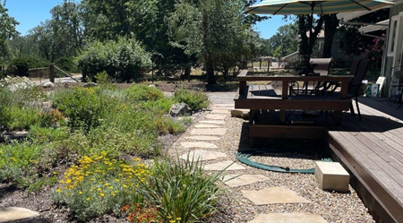 A fire-wise landscape with a deck and pavers closest to the house, then low water plants.