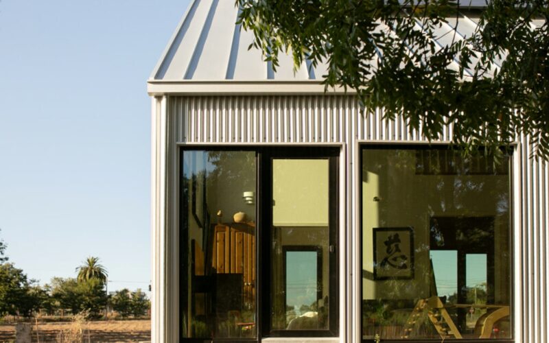 A view through the home's window shows a tidy living room