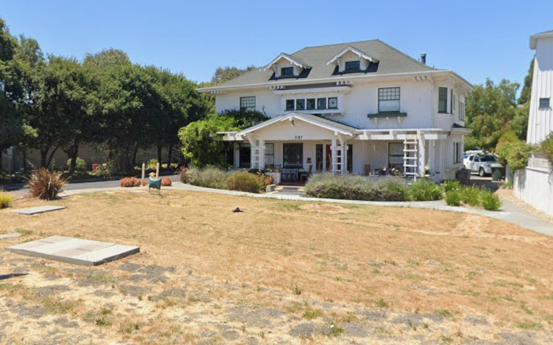 Large white farmhouse with an expansive brown lawn prior to landscape transformation